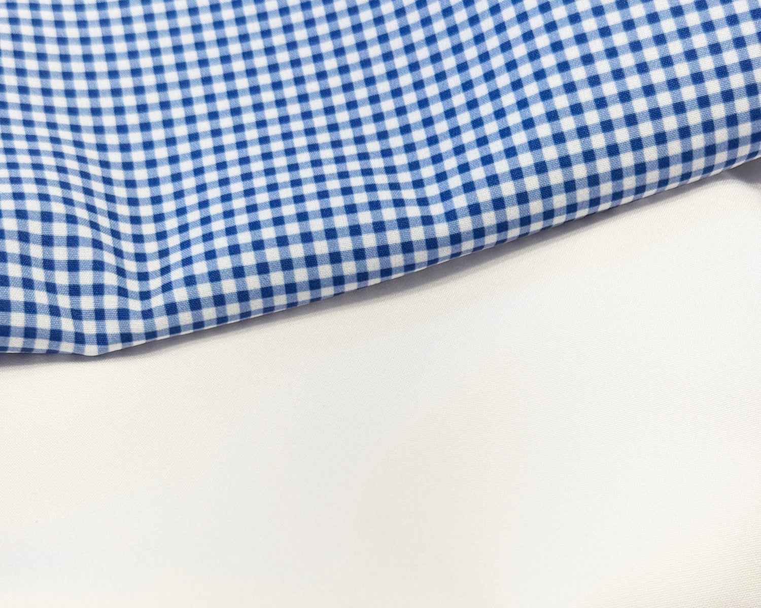 Close-up of blue and white checkered fabric, white plain fabric, and navy textured fabric.