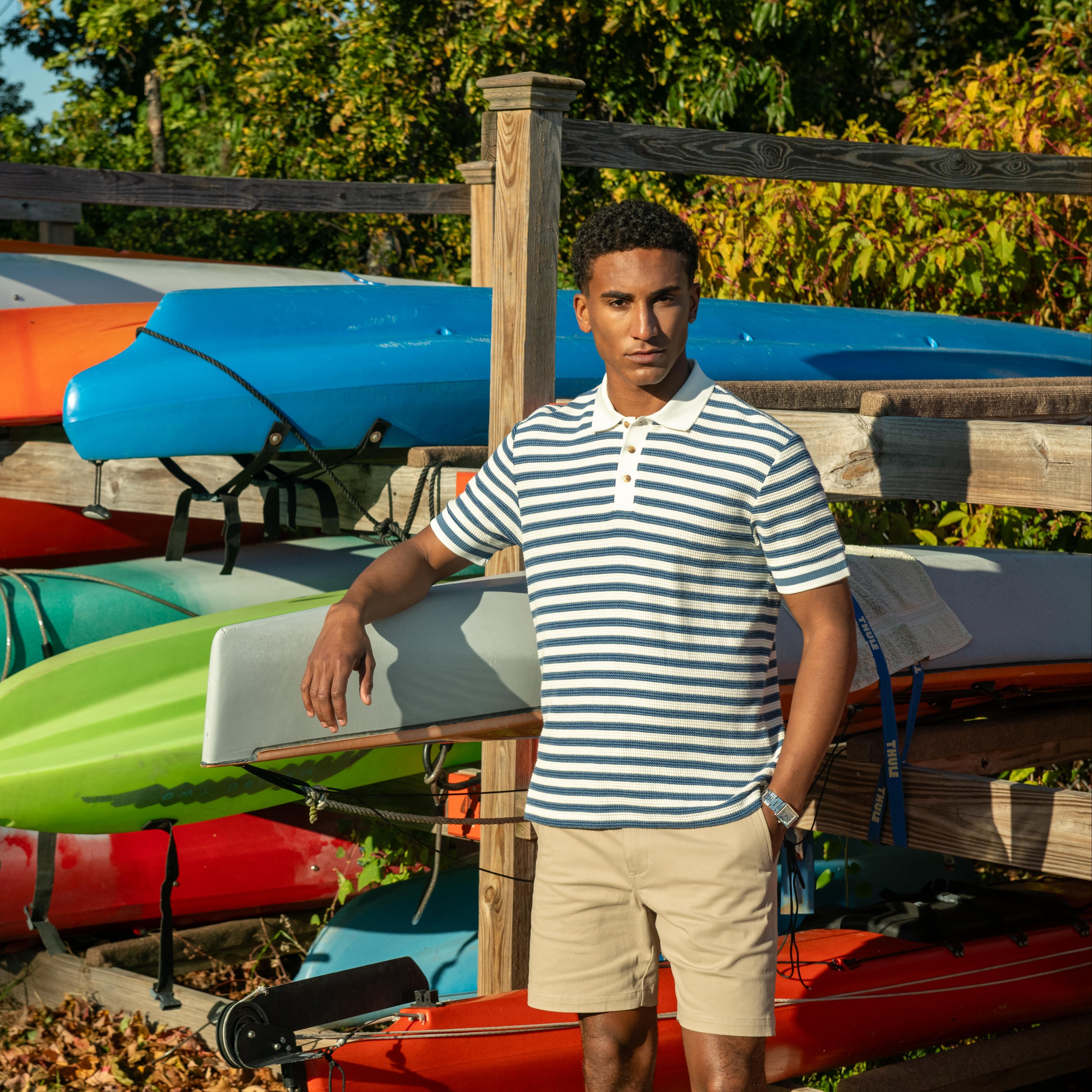 Man holding a paddle in front of kayaks at a dock with 'Shady Kayak Racks' sign.