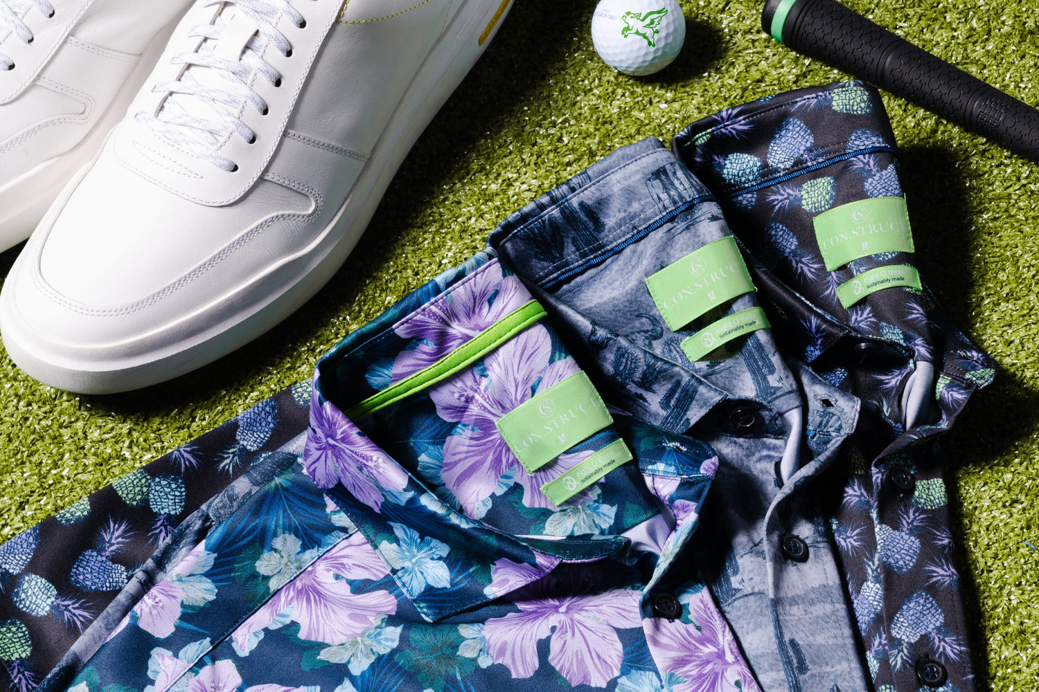 A styled flat-lay of a white leather sneaker with yellow lining, a floral print shirt, golf balls, and a golf club on a green grass background.